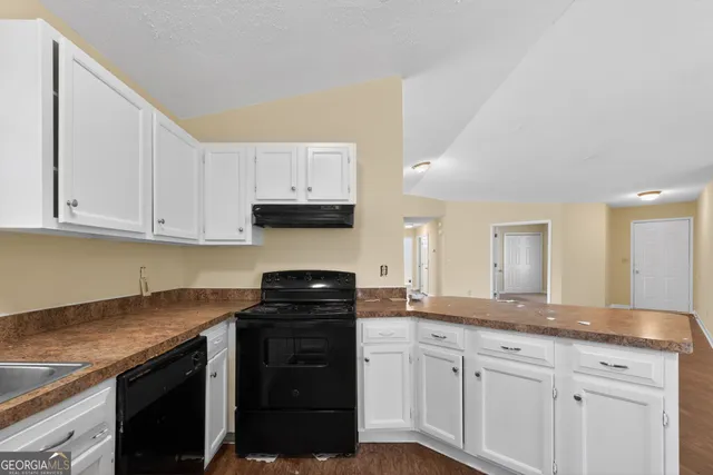 a kitchen with granite countertop a sink a stove and cabinets