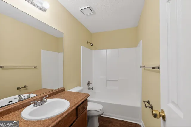 a bathroom with a granite countertop sink toilet a mirror and shower