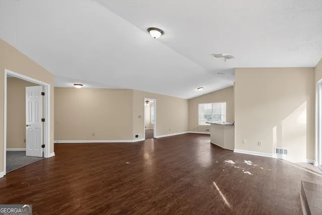 a view of an empty room with wooden floor and window