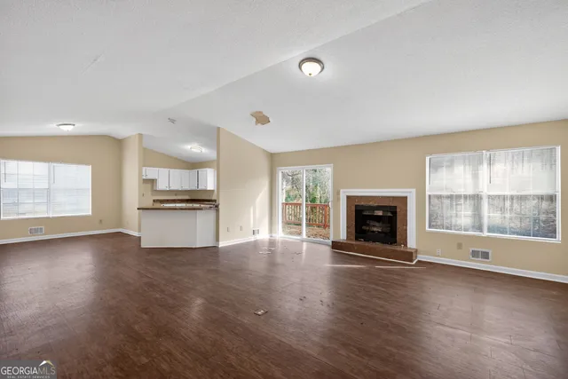 an empty room with kitchen view and a fireplace