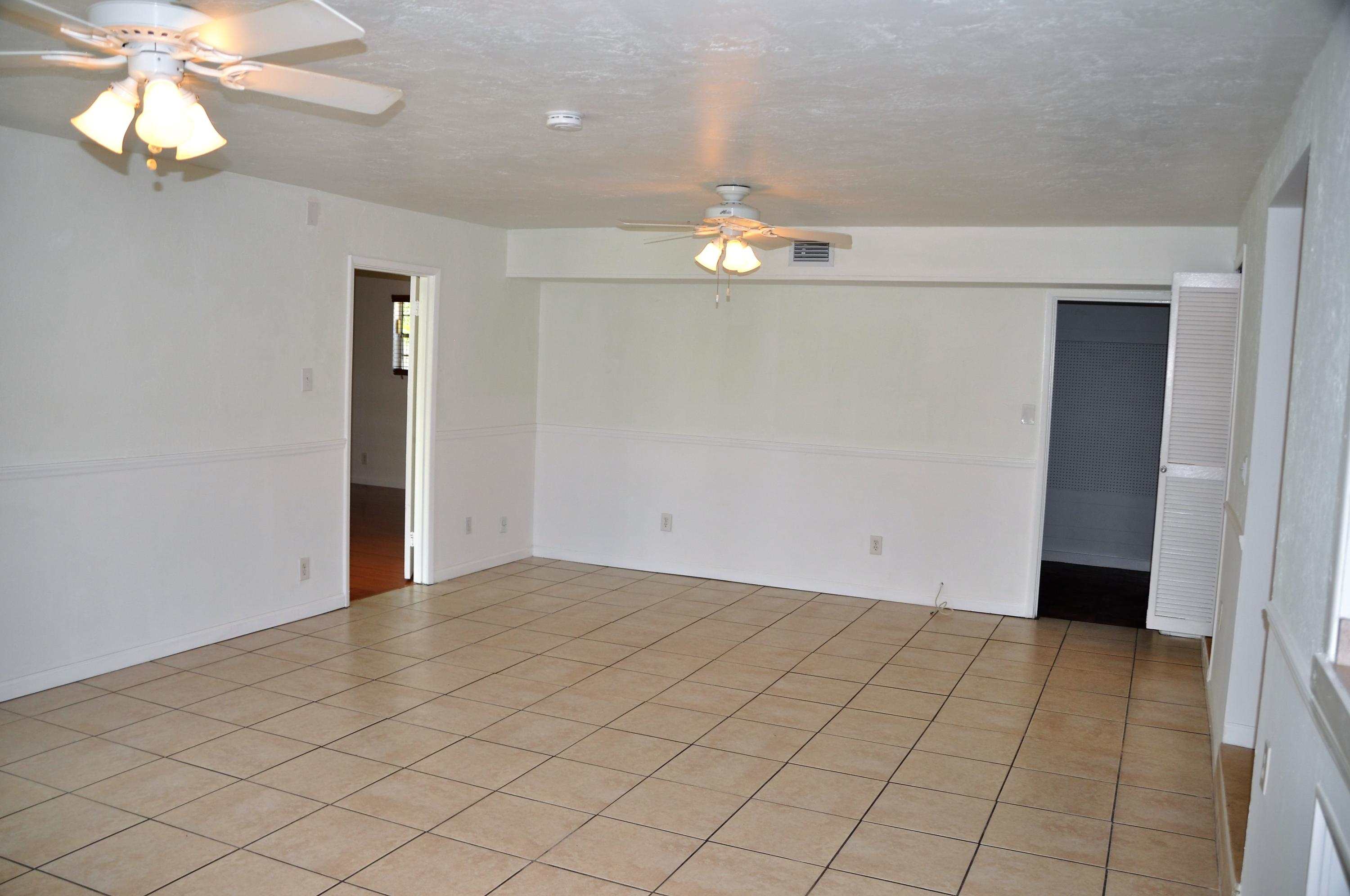 3025 Robert Road West Palm Beach, FL 33405 - Photo 8 of 41 an empty room with kitchen view and a chandelier fan