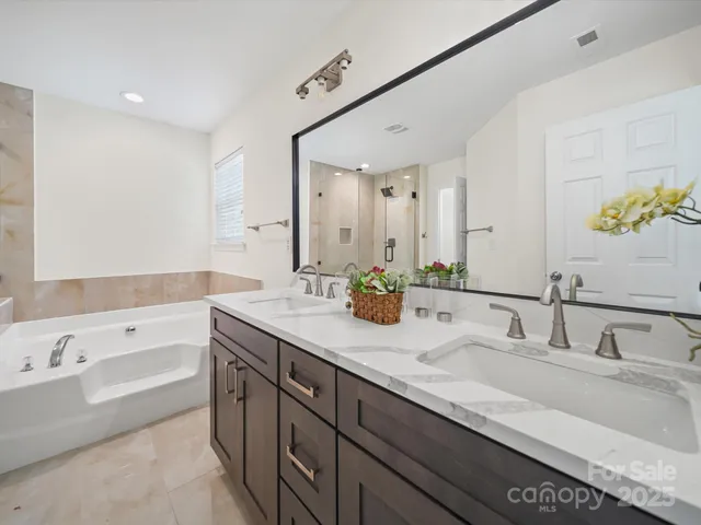 a bathroom with a tub double sink and mirror