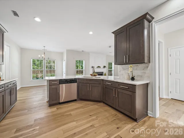 a large kitchen with stainless steel appliances granite countertop a stove a sink dishwasher and white cabinets with wooden floor