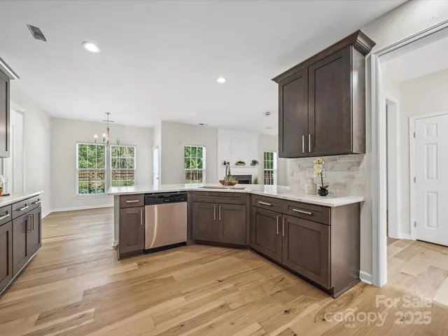 a large kitchen with stainless steel appliances granite countertop a stove a sink dishwasher and white cabinets with wooden floor