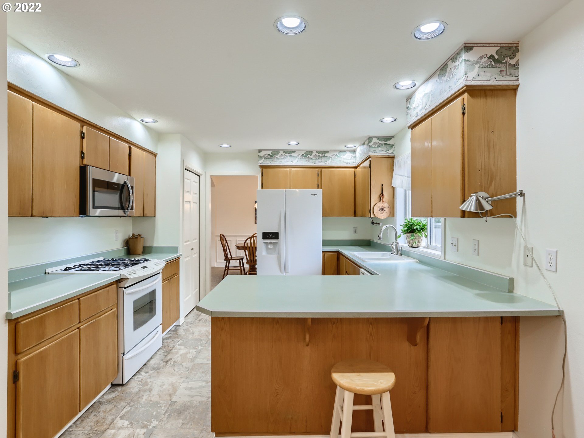 11370 Southwest Clifford Street Beaverton, OR 97008 - Photo 10 of 29 a kitchen with stainless steel appliances granite countertop a sink a stove a refrigerator cabinets and chairs