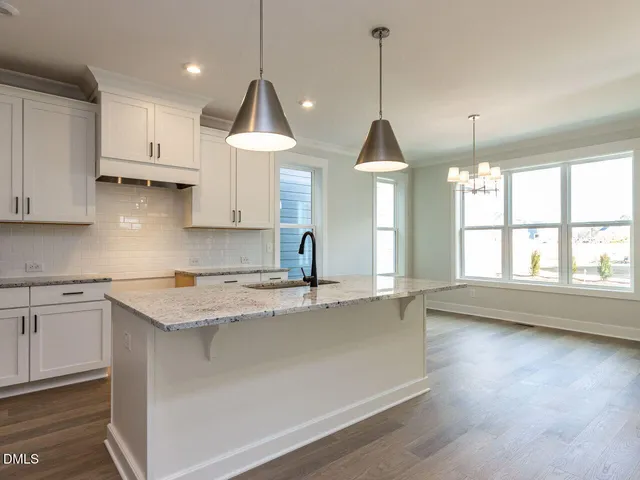 a kitchen with kitchen island granite countertop a stove a sink a center island and wooden floor