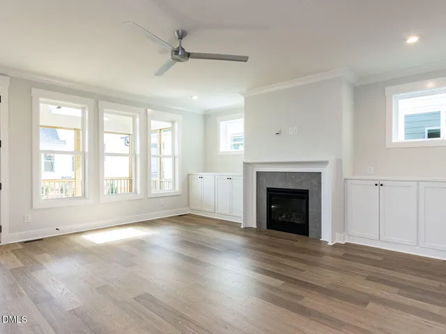 an empty room with wooden floor fireplace and windows