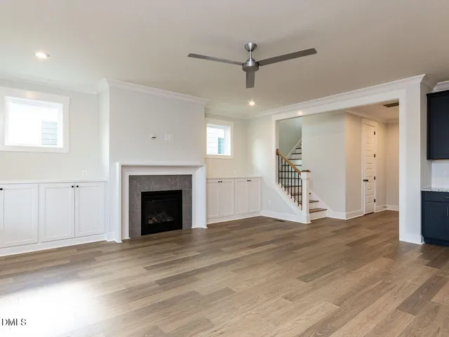 an empty room with wooden floor a fireplace and windows