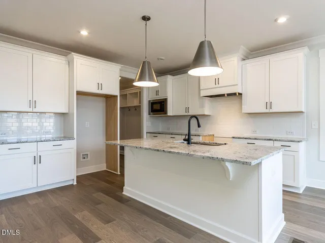 a kitchen with stainless steel appliances granite countertop a sink a stove and a wooden floors