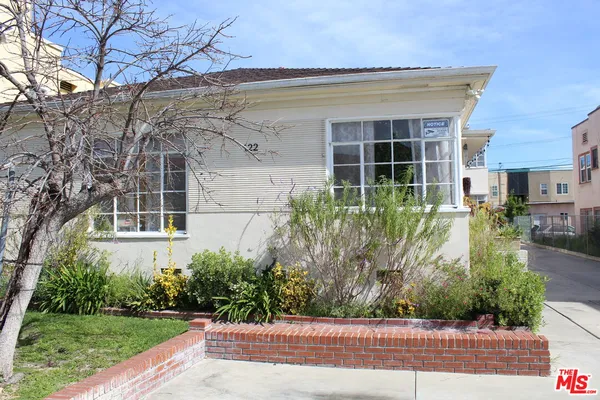 a front view of a house with a yard and potted plants
