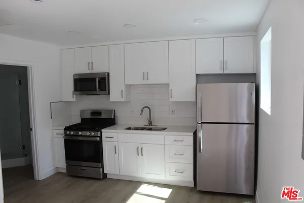 a kitchen with a refrigerator sink and white cabinets