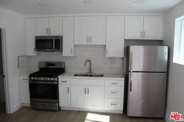 a kitchen with appliances a refrigerator and cabinets