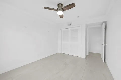 an empty room with windows and fan