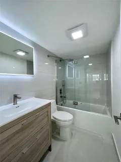 a bathroom with a bathtub shower sink mirror and toilet