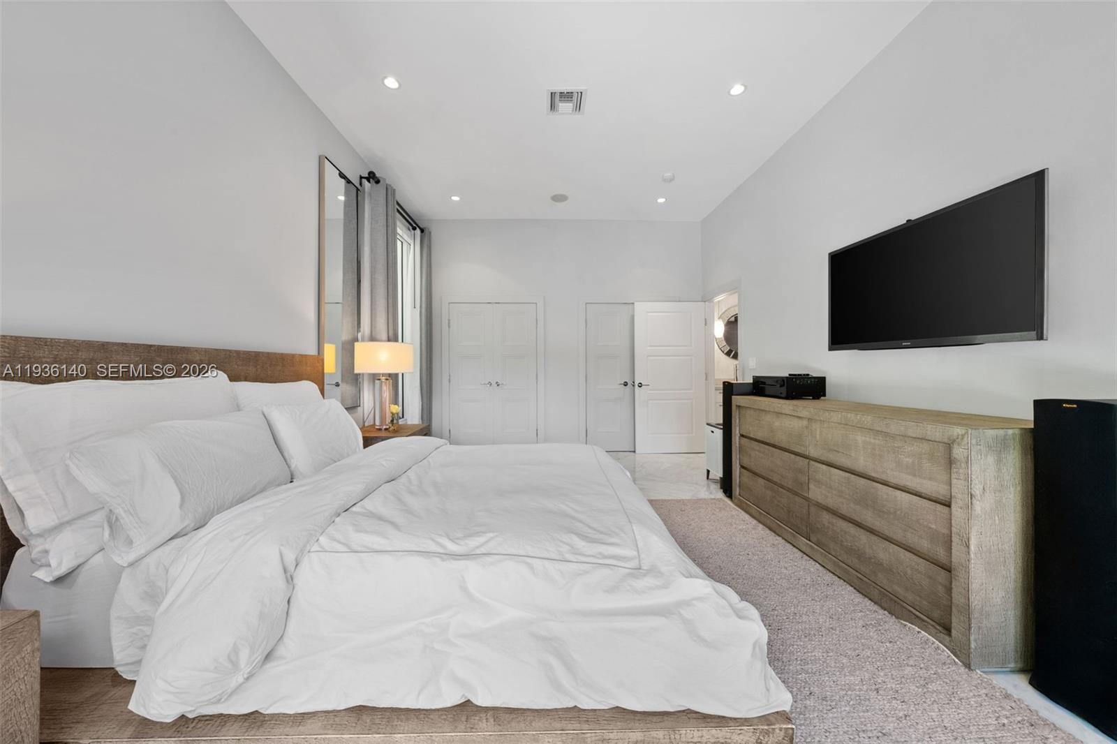 1251 Kane Concourse Bay Harbor Islands, FL 33154 - Photo 17 of 52 a spacious bedroom with a bed and a flat screen television