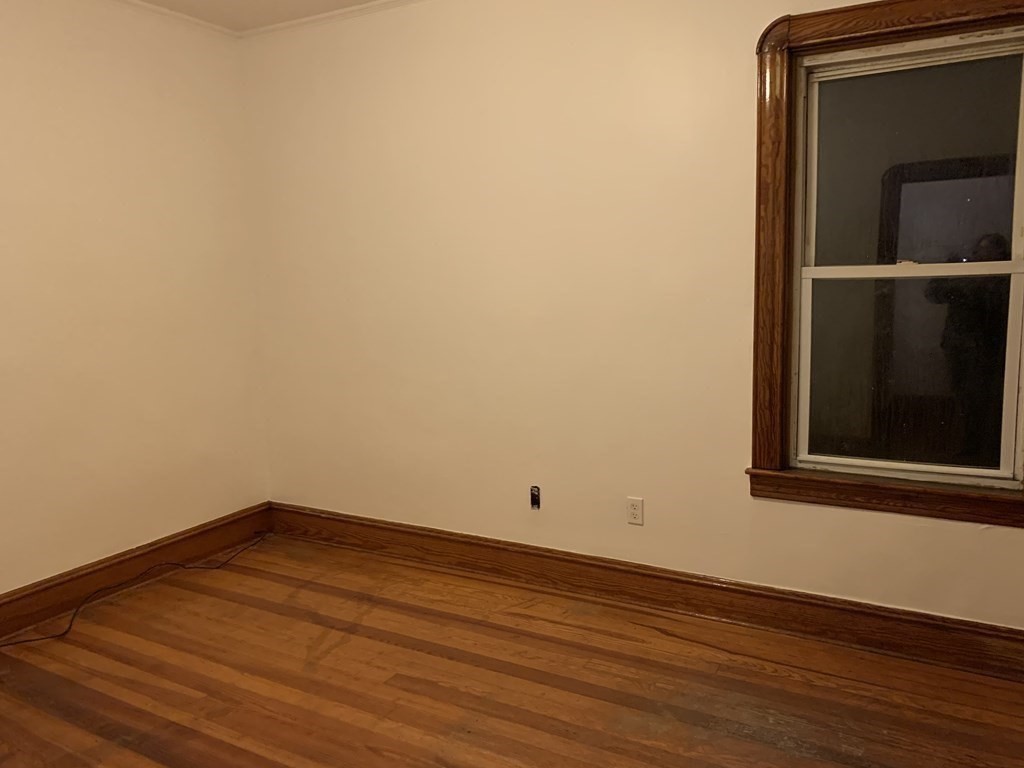 44 Crawford Street, Unit 3 Fall River, MA 02724 - Photo 4 of 8 an empty room with wooden floor and cabinet