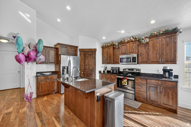 141 Wolverine Creek Elk Ridge, UT 84651 - Photo 9 of 47 Kitchen featuring stainless steel appliances, a center island with sink, dark stone countertops, recessed lighting, and light wood-style flooring