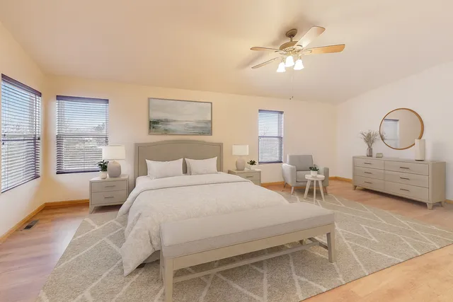 a spacious bedroom with a bed a couch and large windows