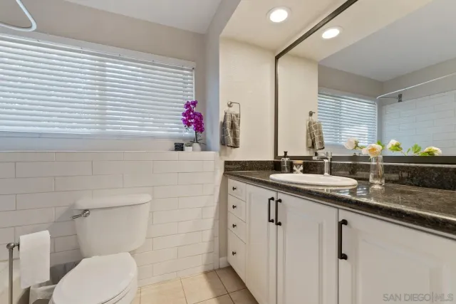 a bathroom with a granite countertop sink toilet a mirror and bathtub