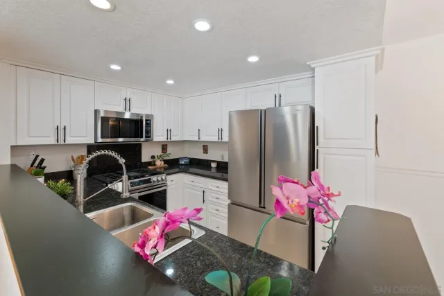 a kitchen with granite countertop a refrigerator and a stove top oven