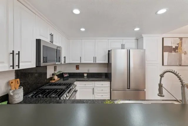 a kitchen with kitchen island stainless steel appliances granite countertop a sink stove and refrigerator