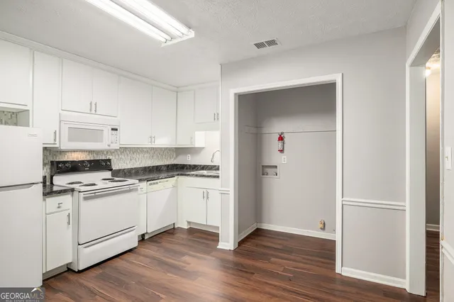 a kitchen with stainless steel appliances granite countertop a stove top oven a sink and white cabinets with wooden floor