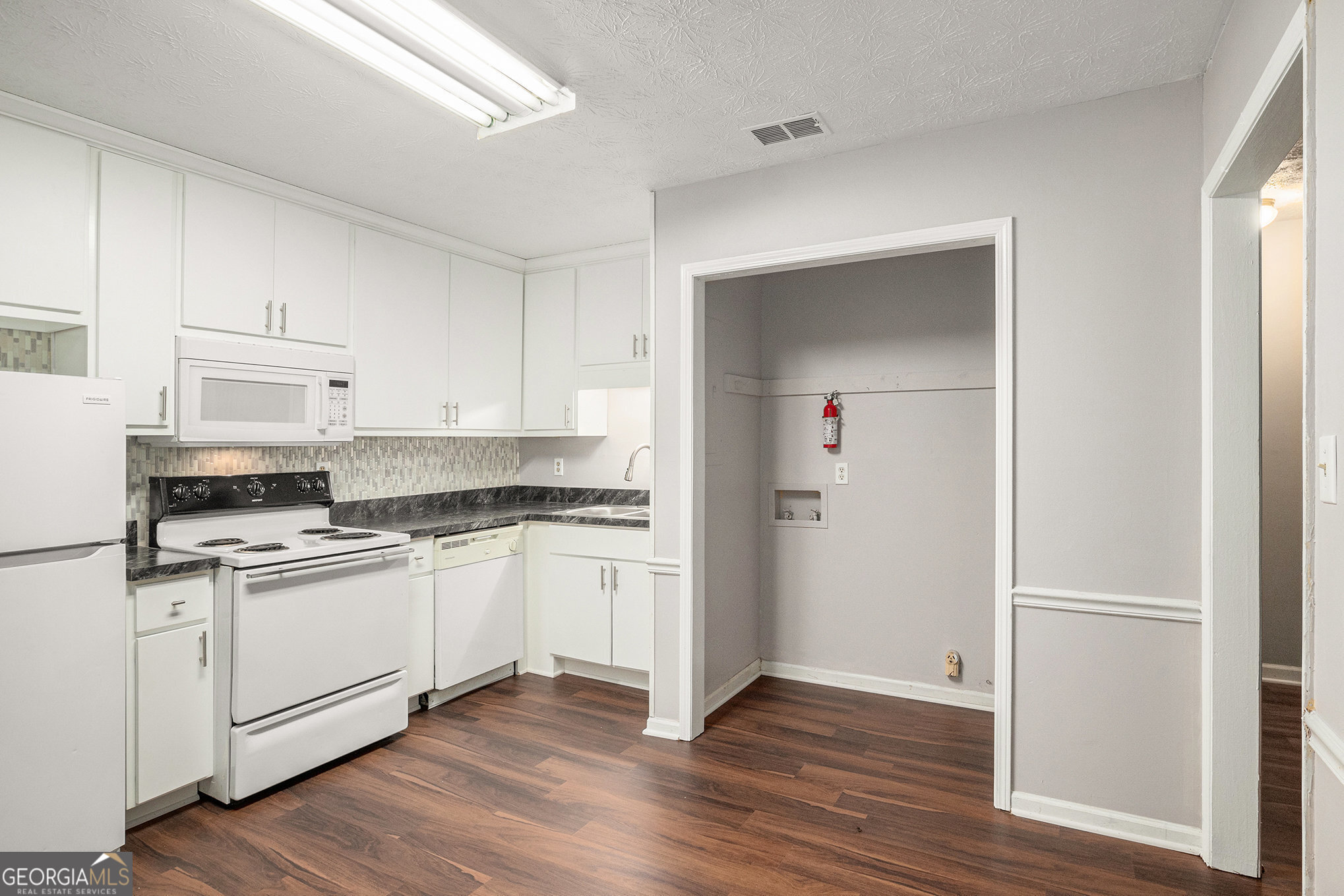 a kitchen with stainless steel appliances granite countertop a stove top oven a sink and white cabinets with wooden floor