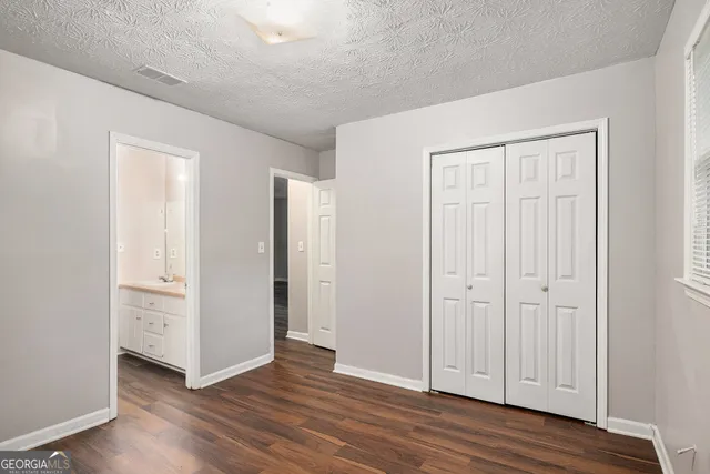 an empty room with wooden floor & closet area