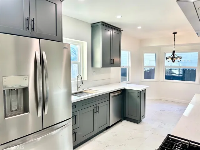 a kitchen with stainless steel appliances granite countertop a refrigerator a sink and a stove