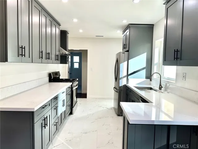a kitchen with kitchen island granite countertop a sink stove and refrigerator