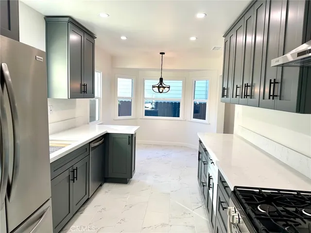 a large kitchen with stainless steel appliances granite countertop a sink and a refrigerator