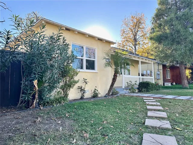 a backyard of a house with potted plants and large tree