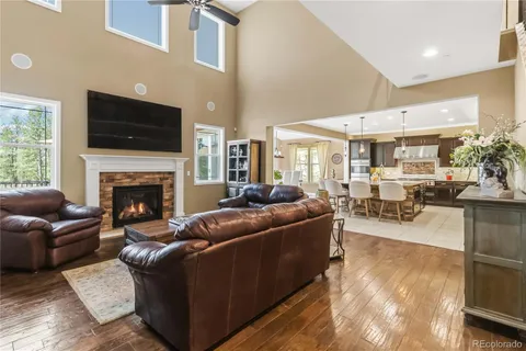 a kitchen with stainless steel appliances kitchen island granite countertop a refrigerator a stove a kitchen island a dining table and chairs with wooden floor
