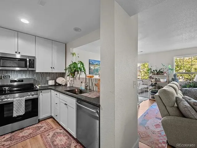 a kitchen with stainless steel appliances granite countertop a sink a stove and a refrigerator