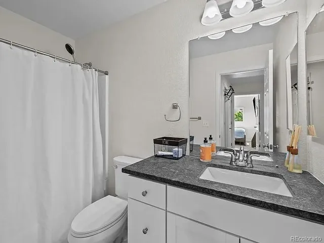a bathroom with a granite countertop sink toilet and mirror