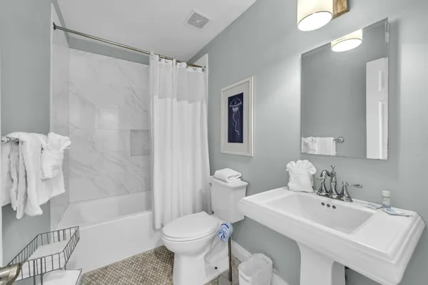a bathroom with a toilet a sink a mirror and a window