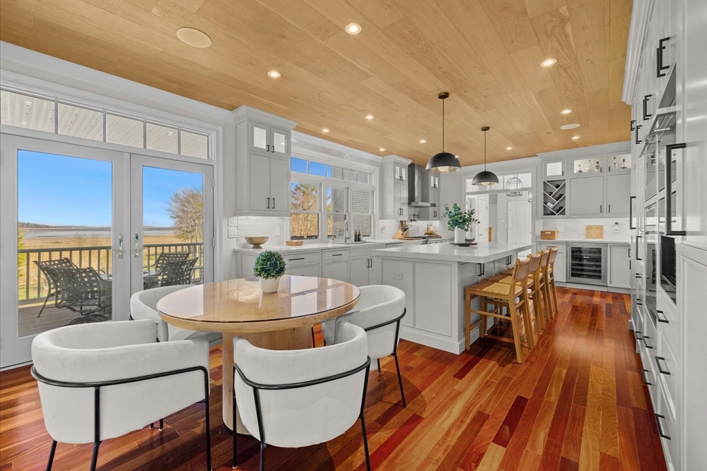 735 Bay Road Duxbury, MA 02332 - Photo 10 of 40 a dining room with stainless steel appliances a dining table wooden floor and a kitchen view