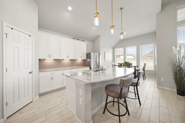 a kitchen with stainless steel appliances granite countertop a sink a stove a refrigerator and island with wooden floor