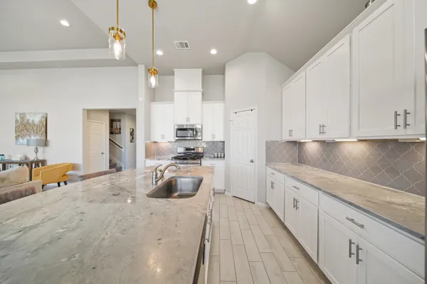 a large kitchen with kitchen island a large counter space a sink appliances and cabinets