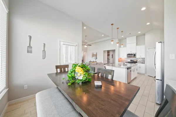 a kitchen with stainless steel appliances granite countertop a refrigerator a microwave oven a dining table and chairs with wooden floor