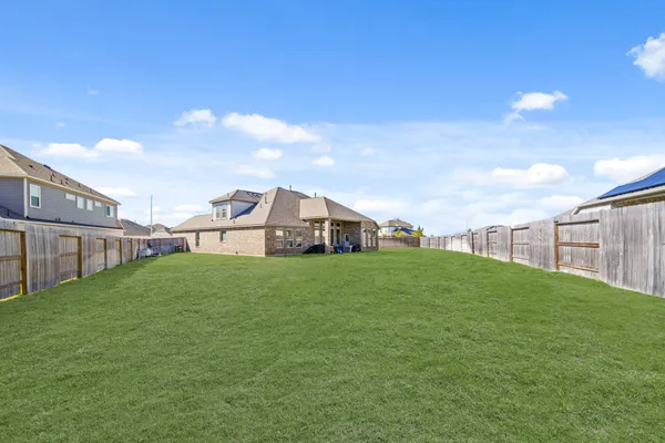 a yellow and red house with a big yard and big trees