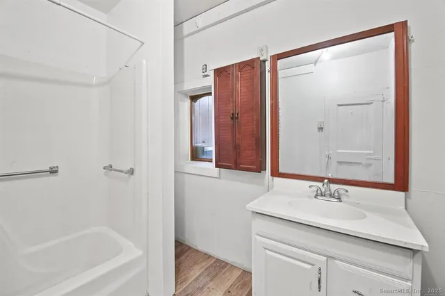 a bathroom with a granite countertop sink a mirror and a bathtub