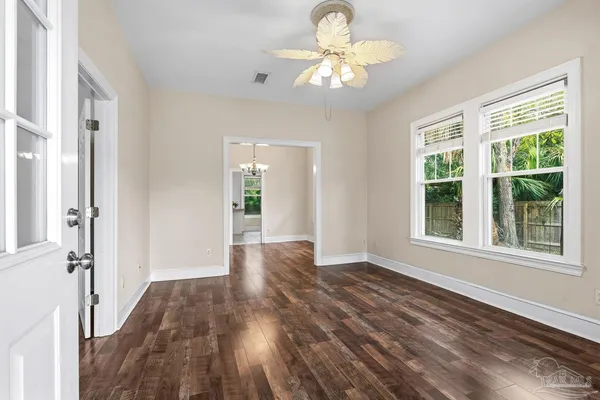 an empty room with wooden floor and windows