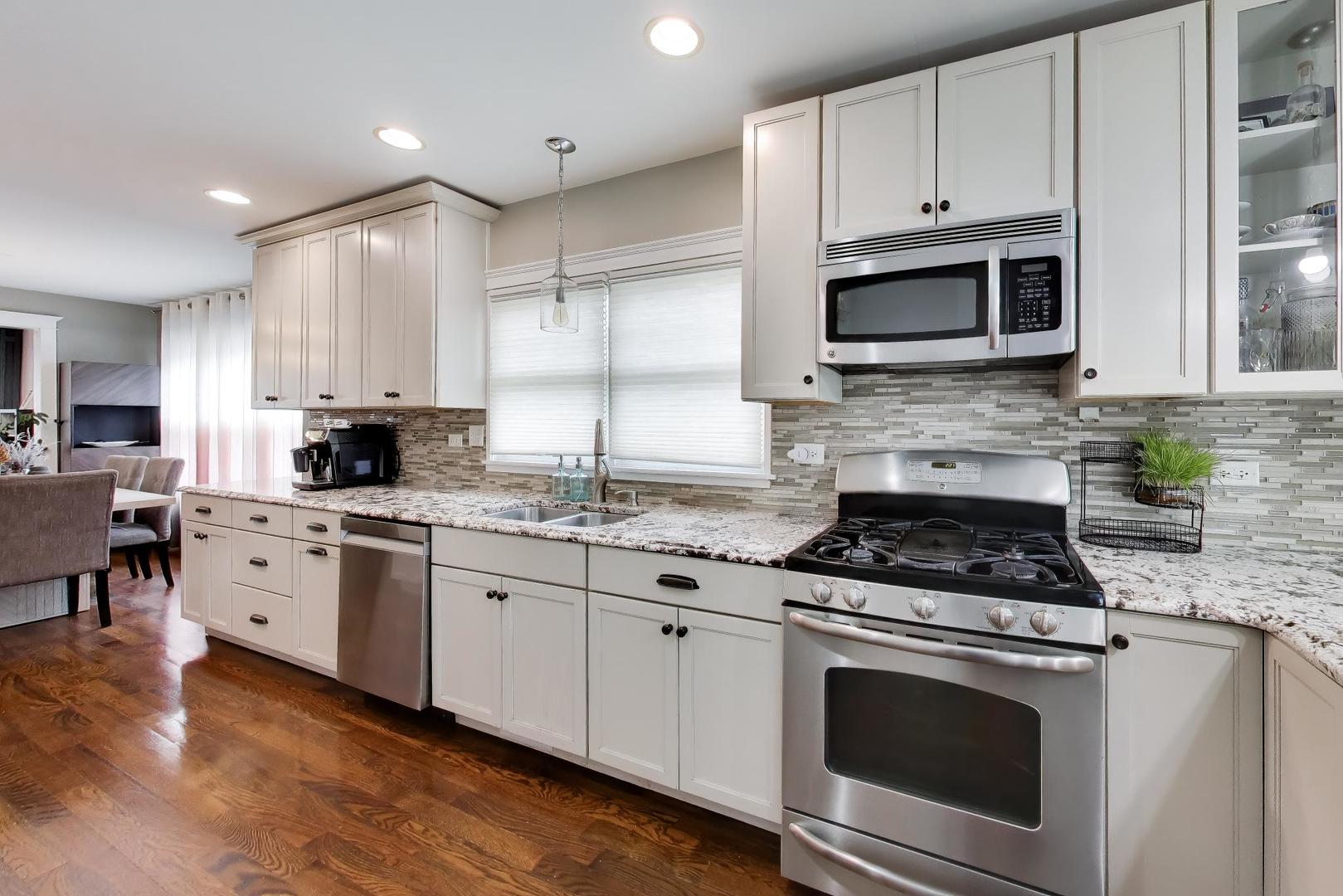 274 Oak Street Elmhurst, IL 60126 - Photo 6 of 31 a kitchen with granite countertop white cabinets stainless steel appliances and wooden floor