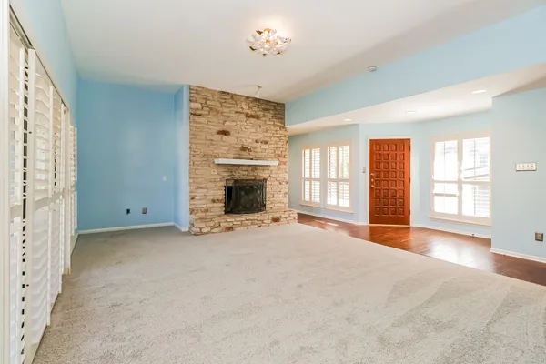 an empty room with windows and fireplace