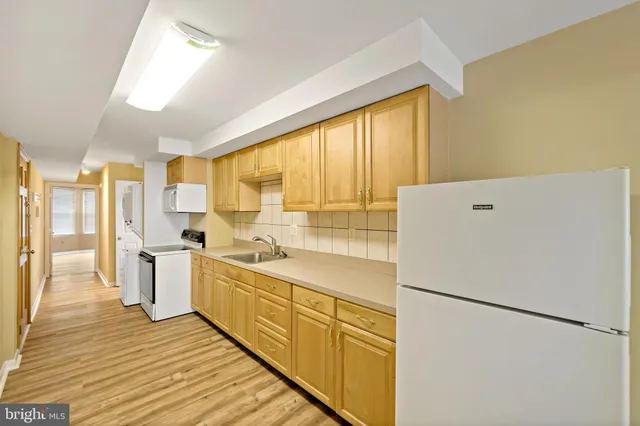 a kitchen with a refrigerator a sink and white cabinets