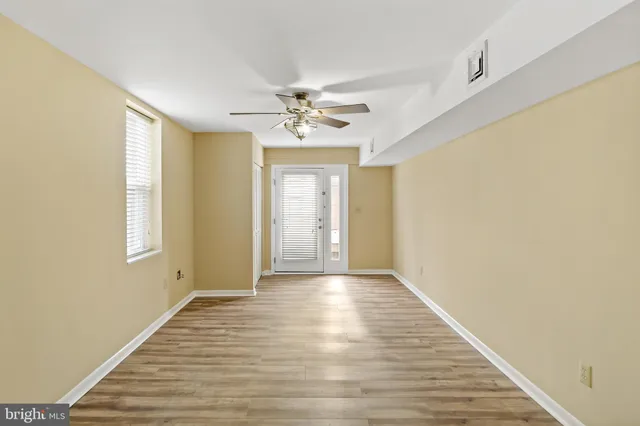 a view of an empty room with window and wooden floor