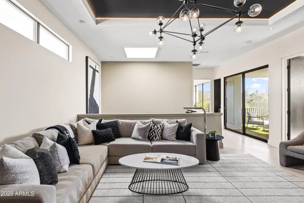 a living room with furniture a flat screen tv and a chandelier
