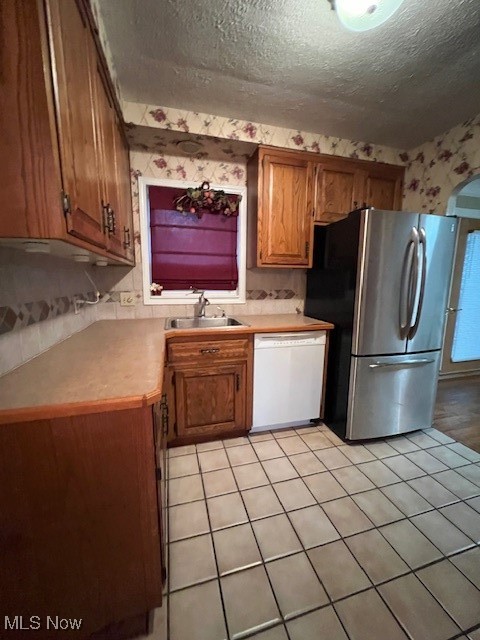 1260 Argonne Road Cleveland, OH 44121 - Photo 12 of 50 Kitchen with sink, dishwasher, fridge, a textured ceiling, and light tile patterned floors