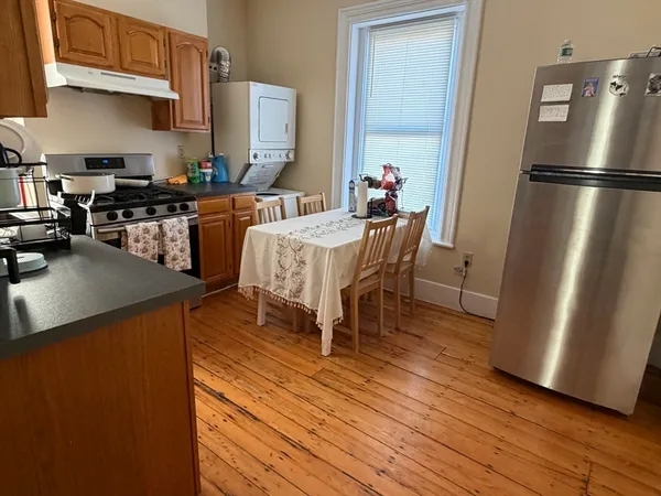 a kitchen with stainless steel appliances a refrigerator a sink a stove a dining table and chairs